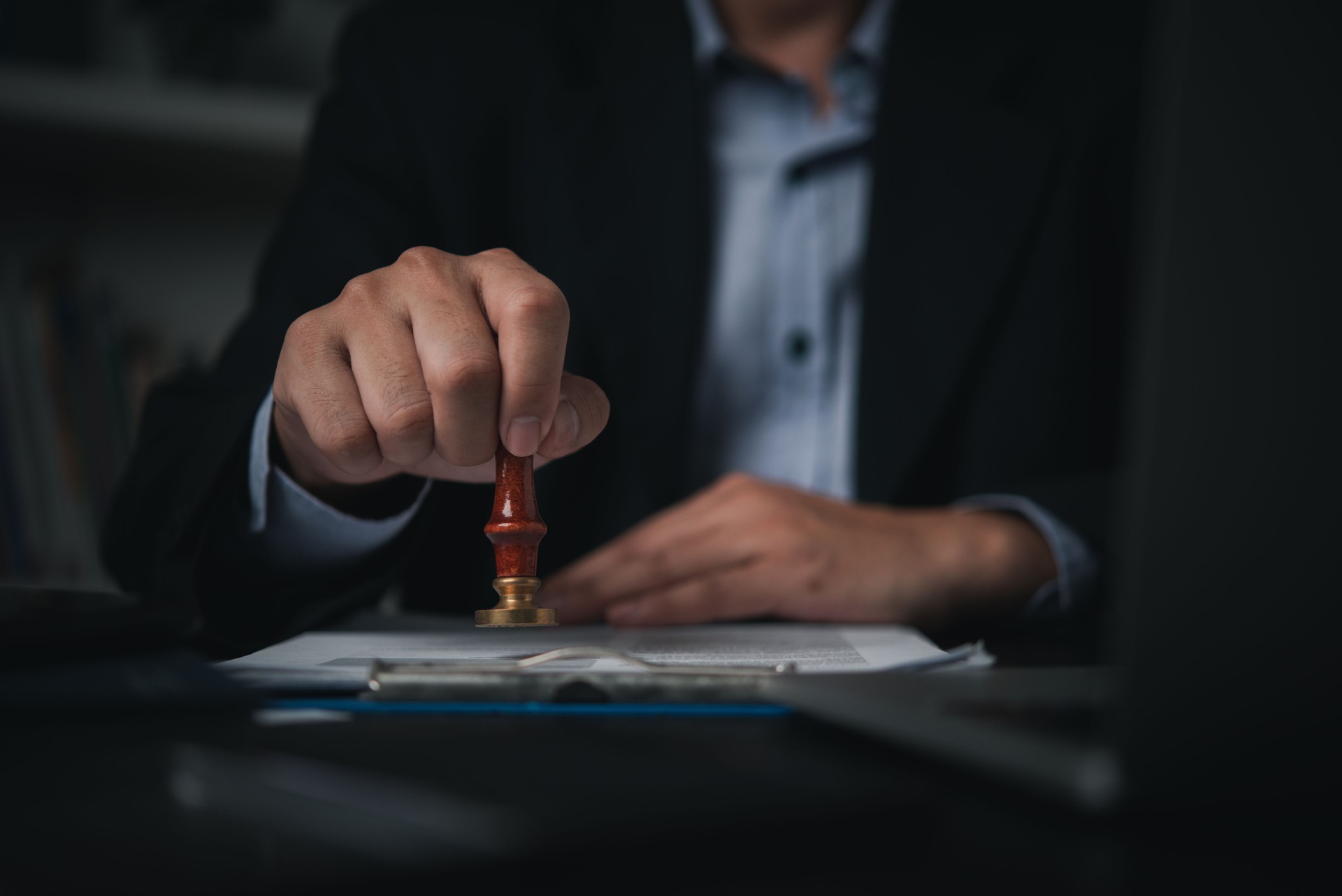 Hand man stamping documents notary public in office . Businessperson stamping approval of work finance banking or investment marketing documents on desk.