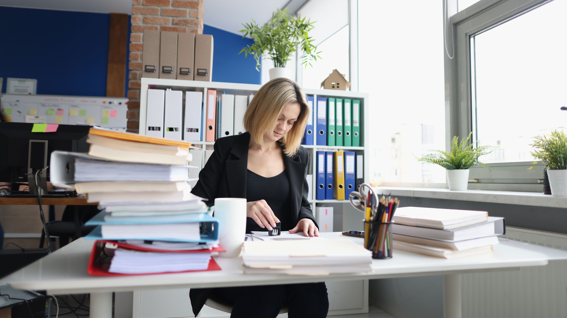 Businesswoman or secretary in office and stamping document